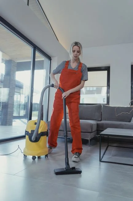 A hotel housekeeper neatly stacks fresh towels in a luxurious room setting.